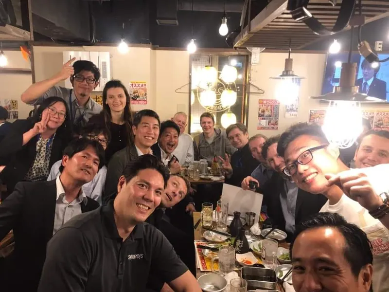 Selfie einer großen, gut gelaunten Runde an einem Tisch in einem japanischen Lokal.